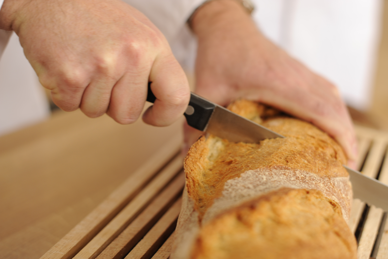 Bäcker schneidet ein Weißbrot