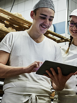 Zwei Bäcker besprechen etwas und schauen auf ein Klemmbrett