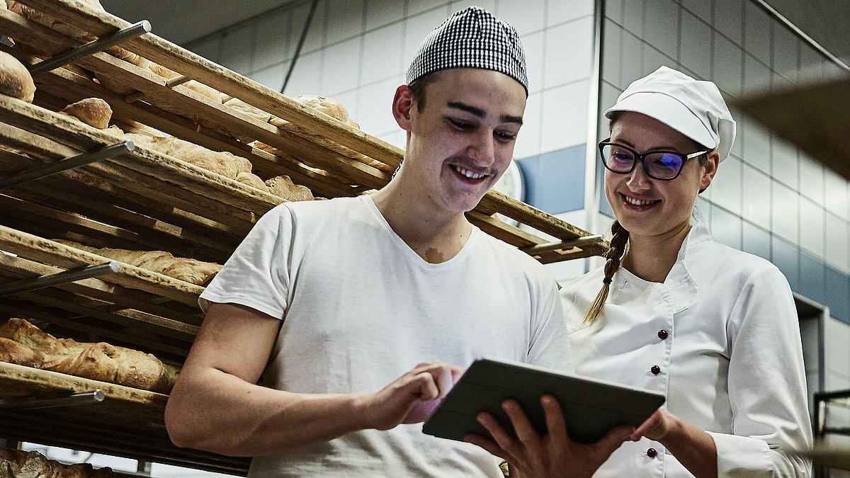 Zwei Bäcker besprechen etwas und schauen auf ein Klemmbrett