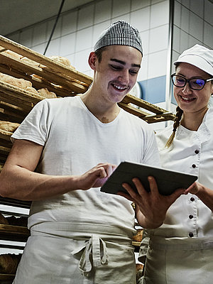 Zwei Bäcker besprechen etwas und schauen auf ein Klemmbrett