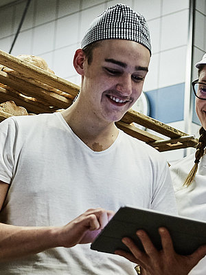 Zwei Bäcker besprechen etwas und schauen auf ein Klemmbrett