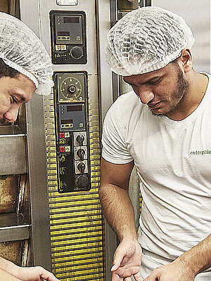 Bäcker nehmen frisch gebackenen Kuchen vom Blech