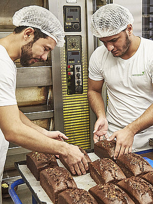 Bäcker nehmen frisch gebackenen Kuchen vom Blech