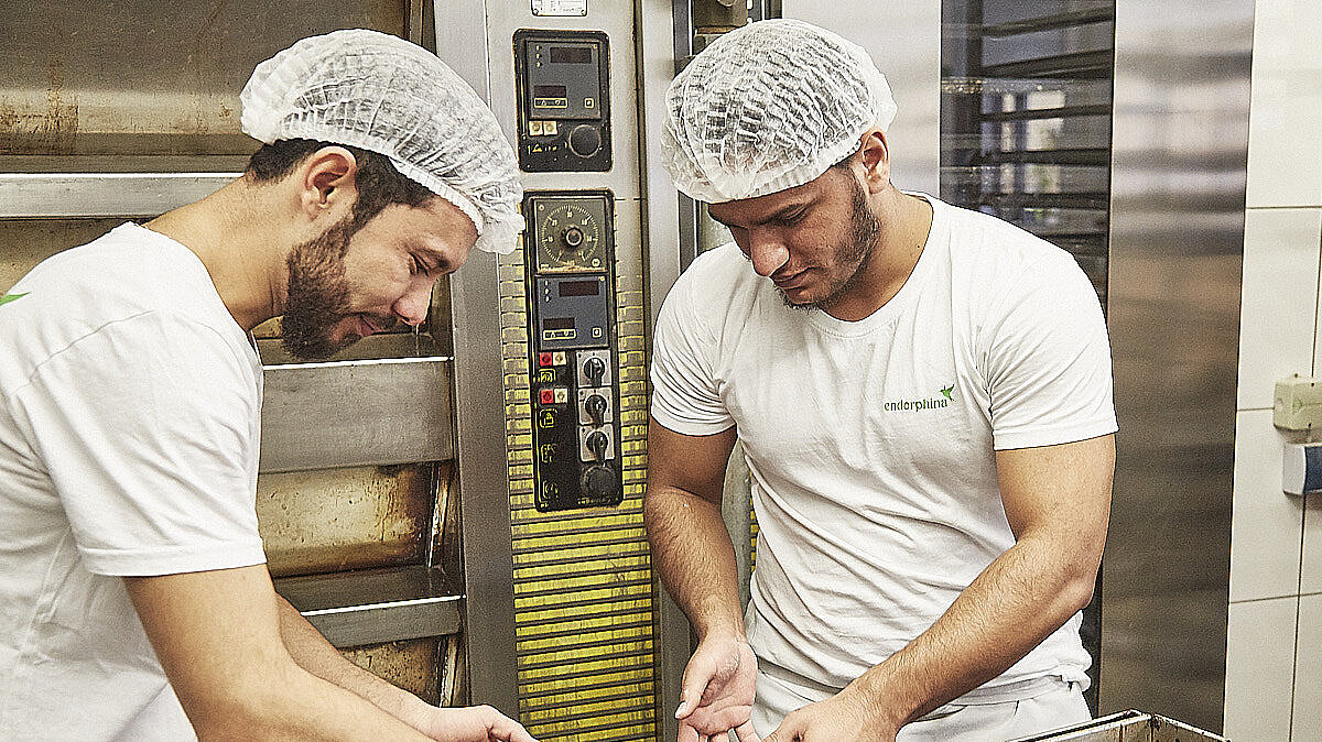 Bäcker nehmen frisch gebackenen Kuchen vom Blech