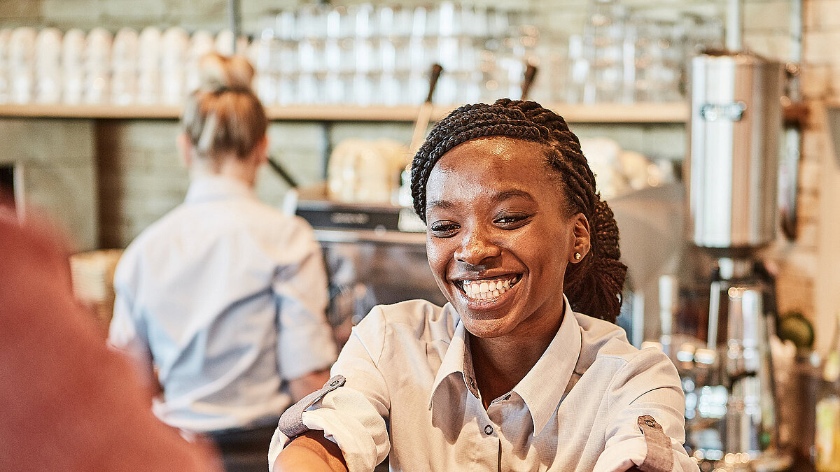 Bäckereifachverkäuferin stellt einen Kaffee auf den Thresen