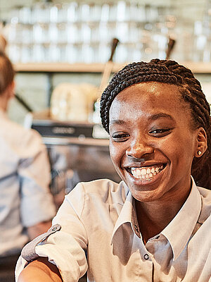 Bäckereifachverkäuferin stellt einen Kaffee auf den Thresen