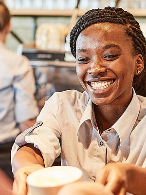 Bäckereifachverkäuferin stellt einen Kaffee auf den Thresen