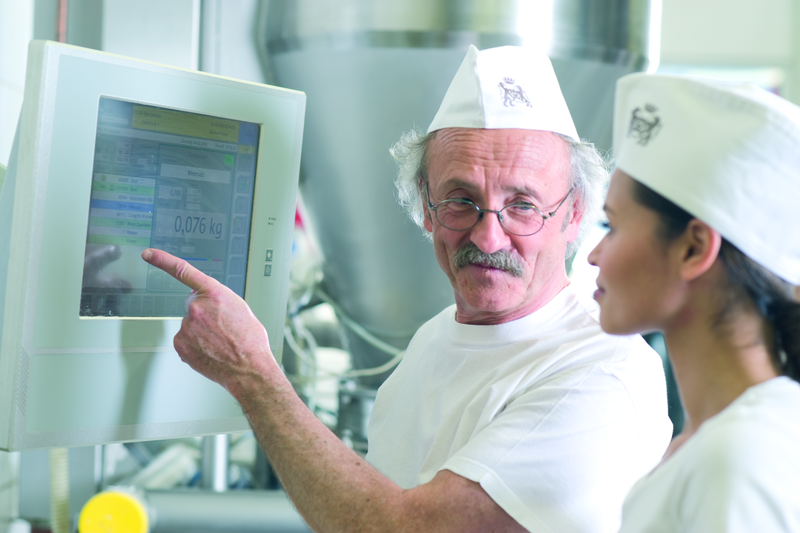 Bäckermeister und Bäckergesellin gucken in den Rezeptcomputer