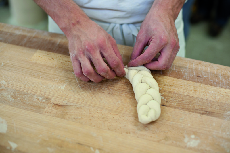 Bäckerazubi flechtet Hefezöpfe