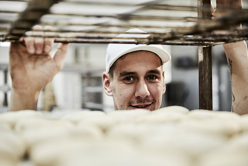 Bäcker Azubi schaut durch Stikkenwagen