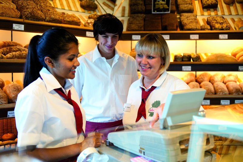 Verkäuferinnen sprechen mit Auszubildendem