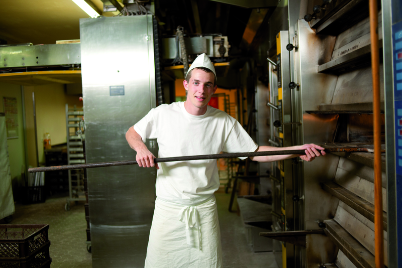 Bäckergeselle am Ofen mit Schieber