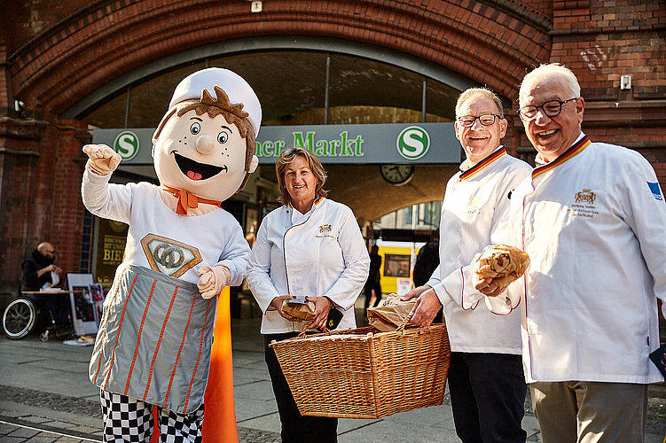 Der Bäckman und drei Bäcker bei einer Brotverteilaktion