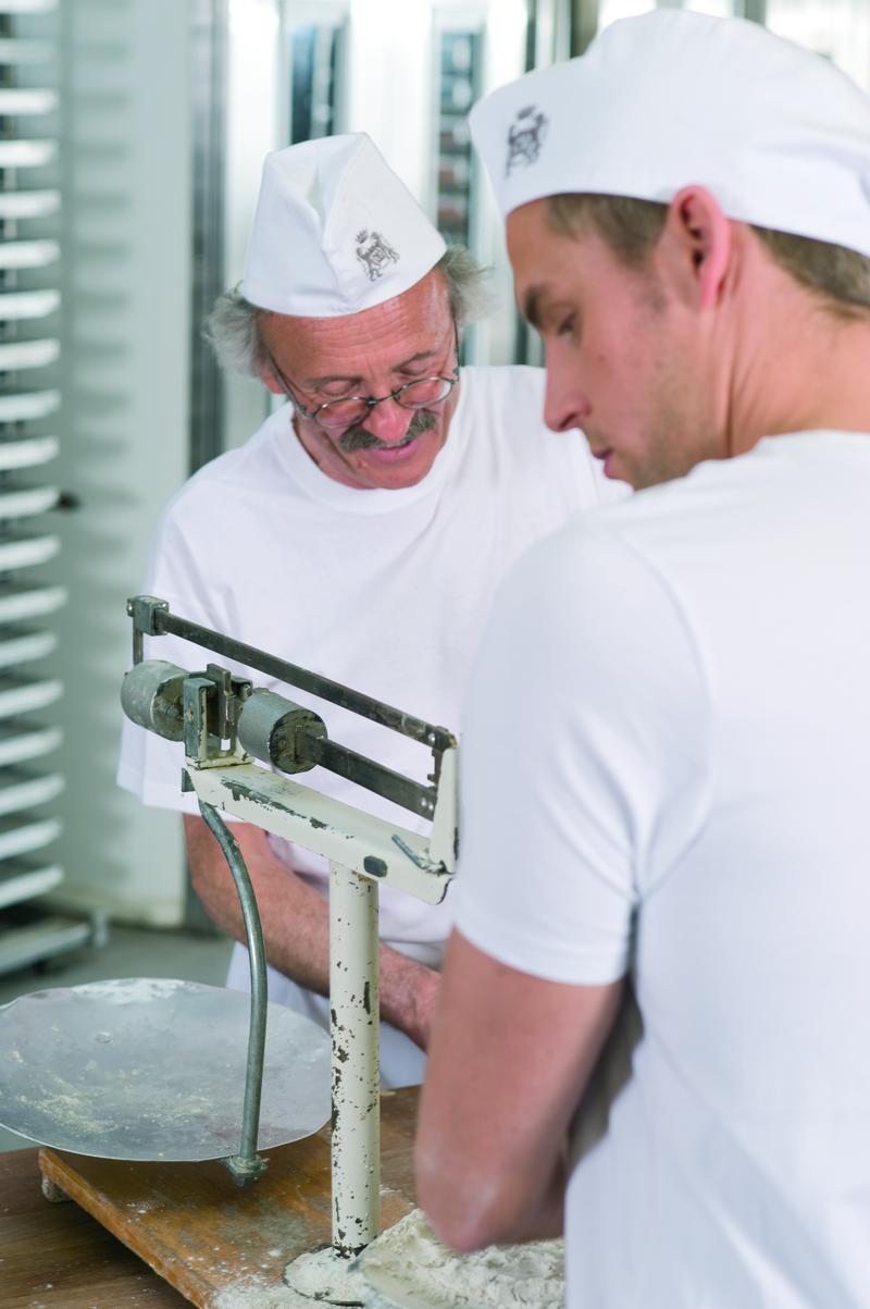 Bäckermeister und Bäckergeselle an der Waage