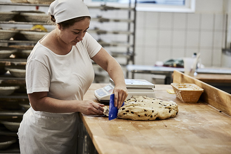 Bäcker Azubine portioniert Teig