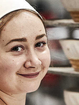 Bäckerin bei der Arbeit, sie lächelt in die Kamera