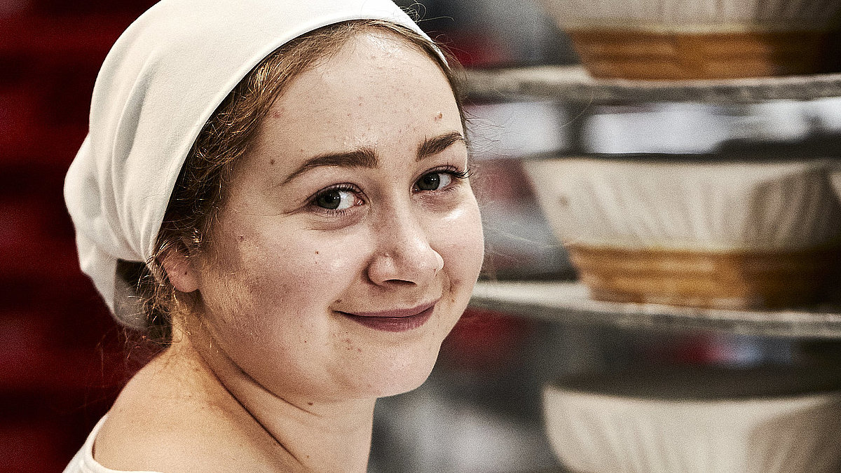 Bäckerin bei der Arbeit, sie lächelt in die Kamera