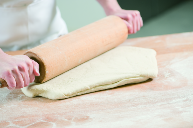 Bäcker formt Teig mit einem Rollholz