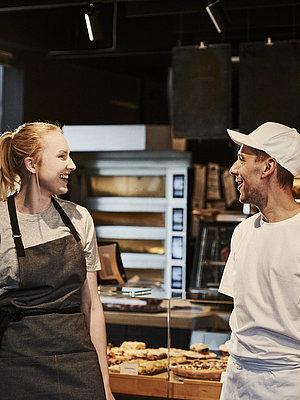Bäckereifachverkäuferin und Bäcker unterhalten sich