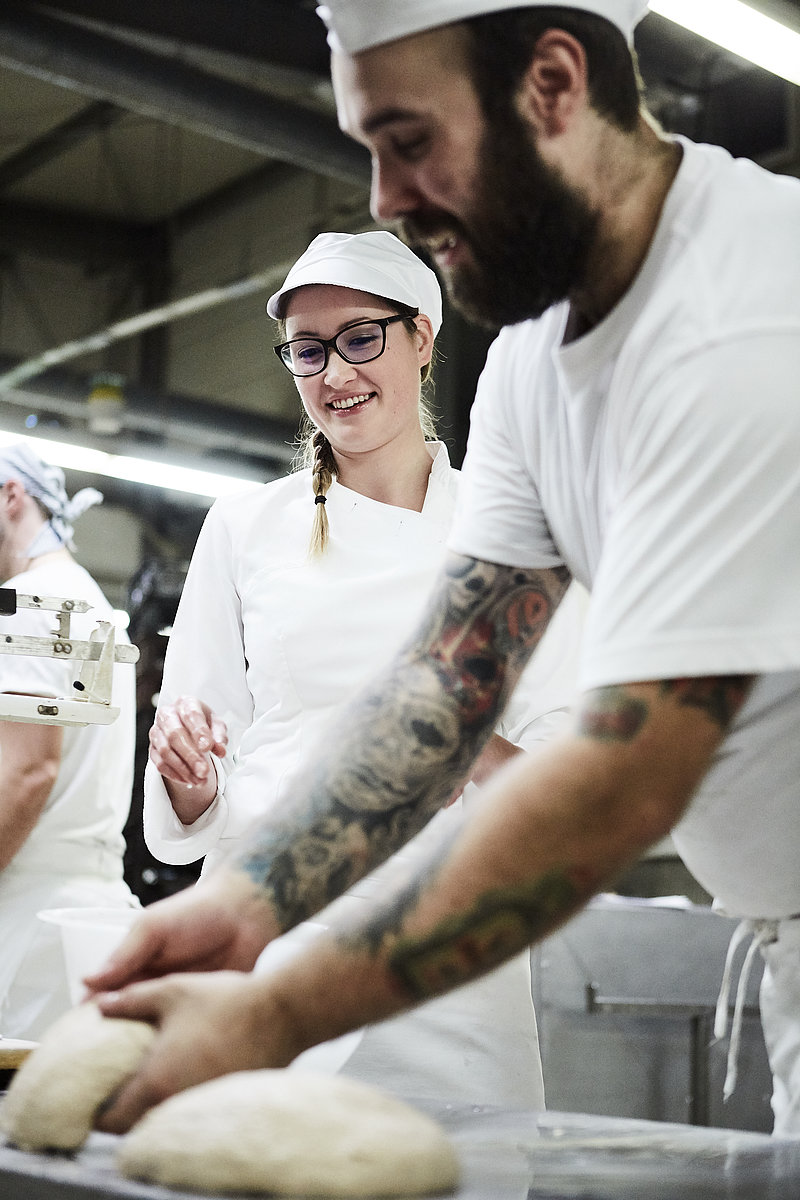 Bäckermeister erklärt Azubine Arbeitsschritte