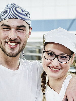Zwei Bäcker, im Hintergrund ein Rollwagen mit Gebäck