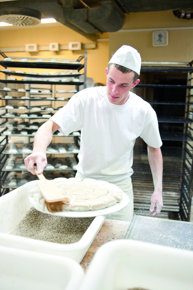 Bäckergeselle bestreicht Teigboden