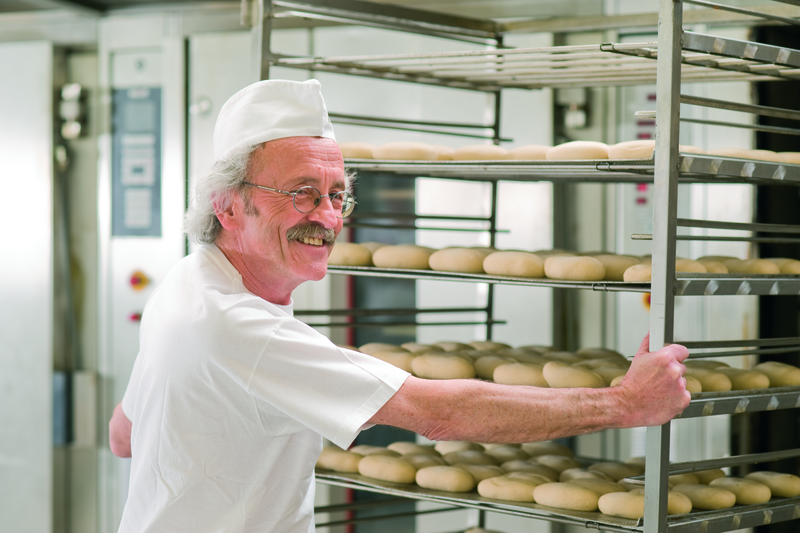 Bäckermeister beschickt einen Stikkenofen mit einem Stikken Brötchenteiglinge