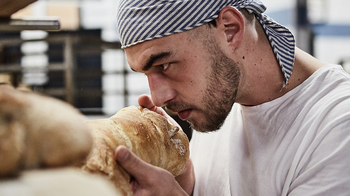 Bäcker riecht an frischen Brötchen