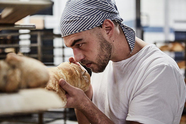 Bäcker riecht an frischen Brötchen