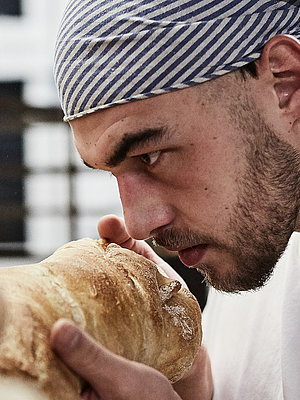 Bäcker riecht an frischen Brötchen