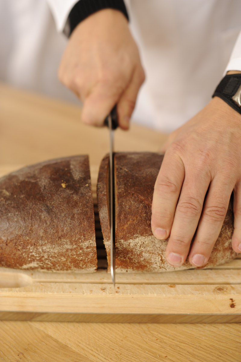 Bäcker schneidet Roggenbrot