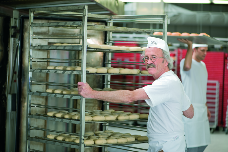 Bäckermeister beschickt einen Stikkenofen mit einem Stikken Brötchenteiglinge