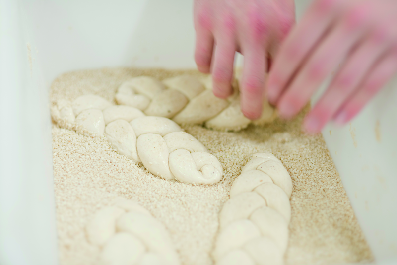 Hefezöpfe werden in Sesam gewälzt