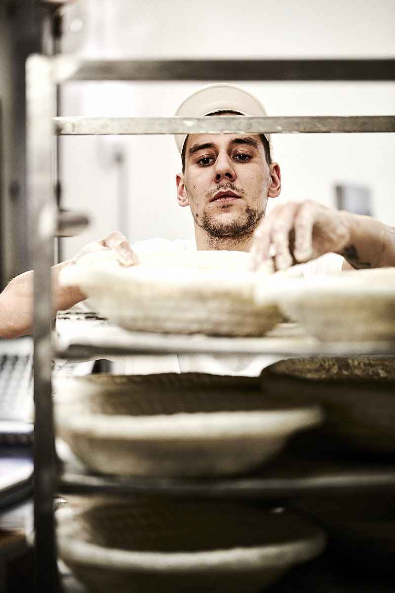 Bäcker Azubi überprüft Teige in Stikkenwagen