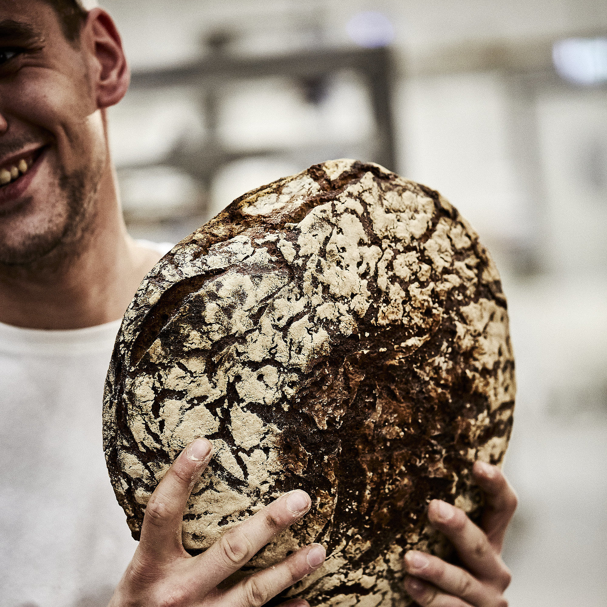 Ein Laib Brot in den Händen eines Bäckers