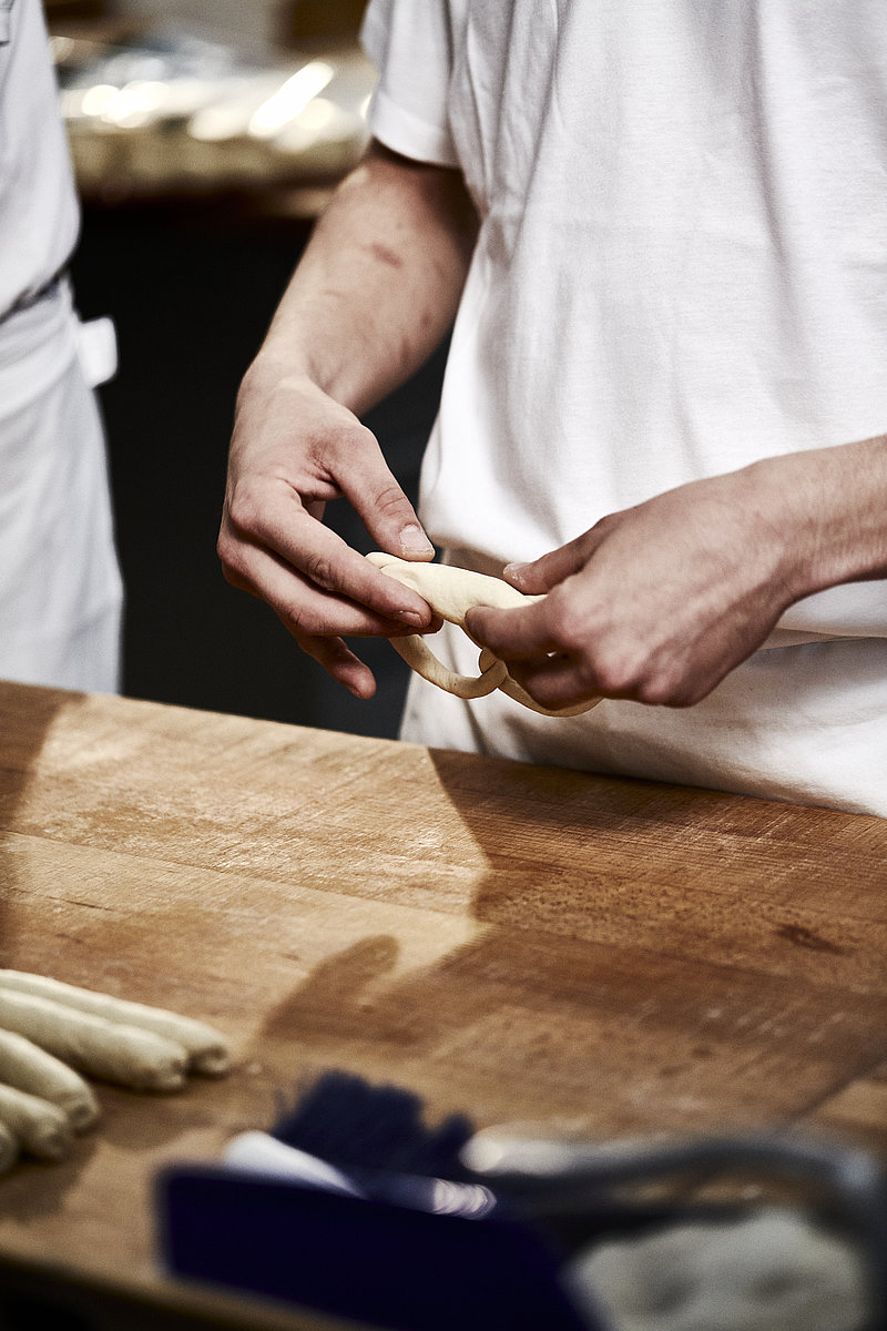 Auszubildender Bäcker formt Brezel