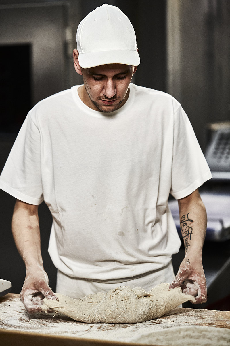 Bäcker Azubi faltet Teig