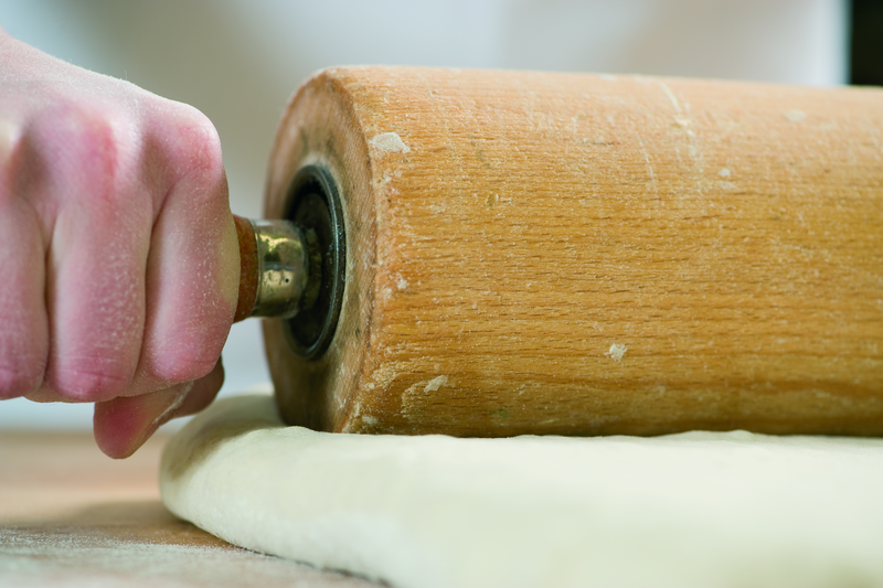 Bäcker formt Teig mit einem Rollholz