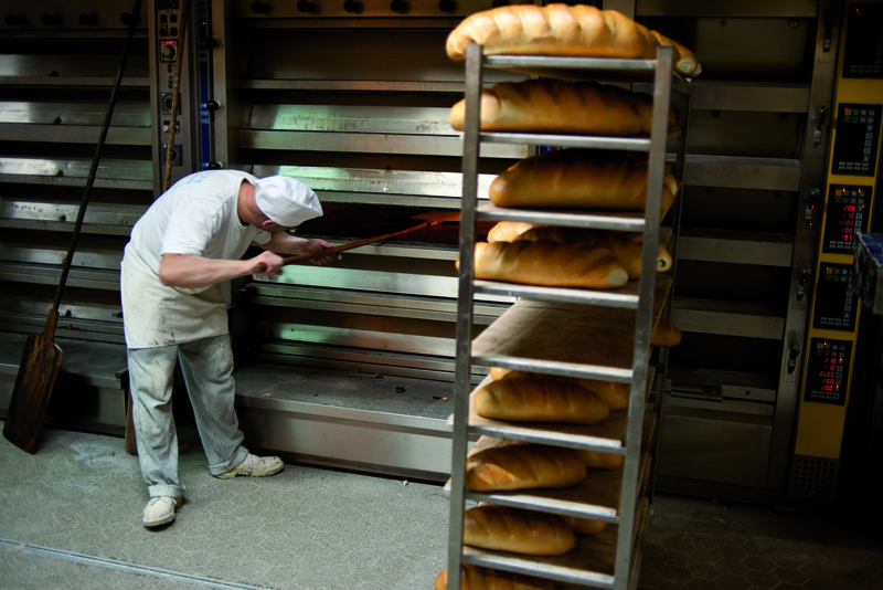 Bäcker schiebt Brot mit Schießer im Ofen