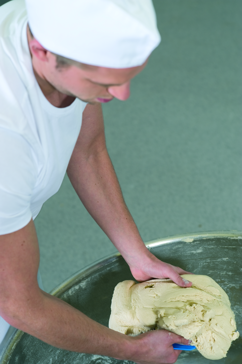 Bäckergeselle holt mit einem Horn einen Ballen aus einer Schüssel