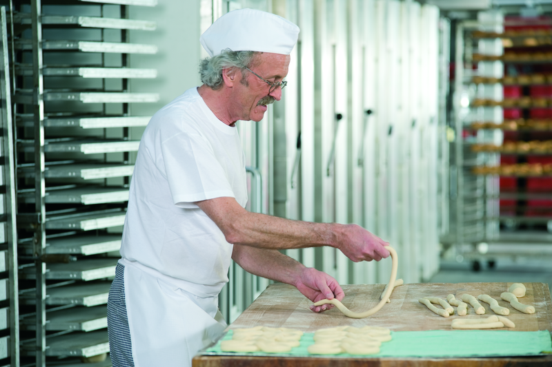 Bäckermeister formt Teig zu einer Brezel