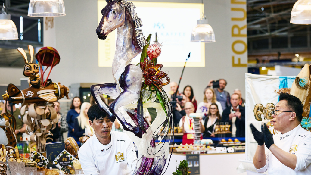 2 Bäcker mit einem Kunstwerk in Form eines Pferdes auf der Iba 2023