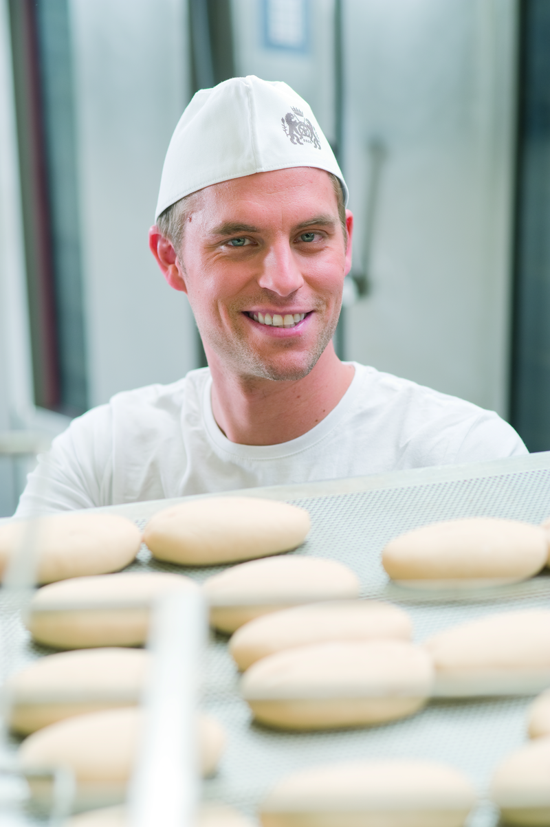 Bäckergeselle begutachtet Brötcheteiglinge