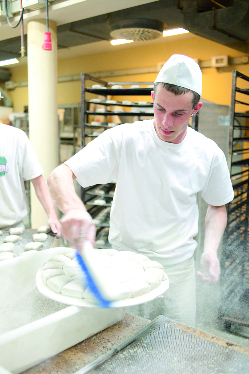 Bäckergeselle zieht Tortenboden glatt