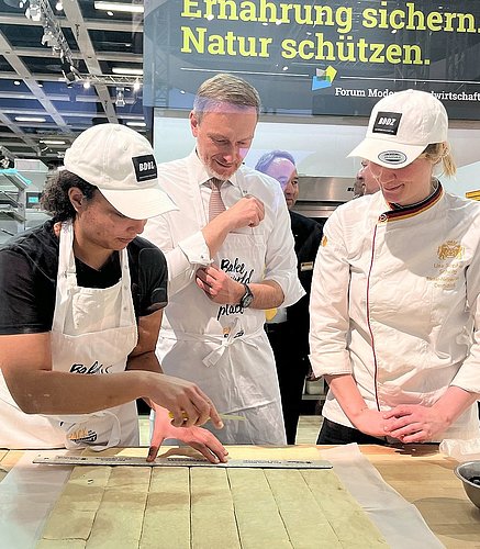 Zwei Bäckerinnen zeigen Christian Lindner von der Partei FDP einen Arbeitsschritt