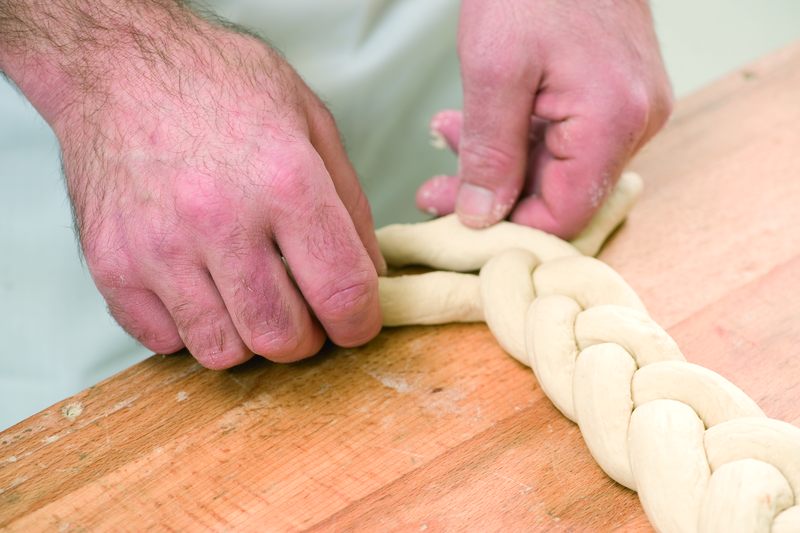 Bäcker formt Teig zu einem Zopf