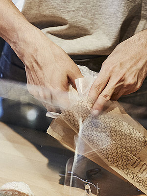 Person packt Backwaren in eine Brötchentüte. 