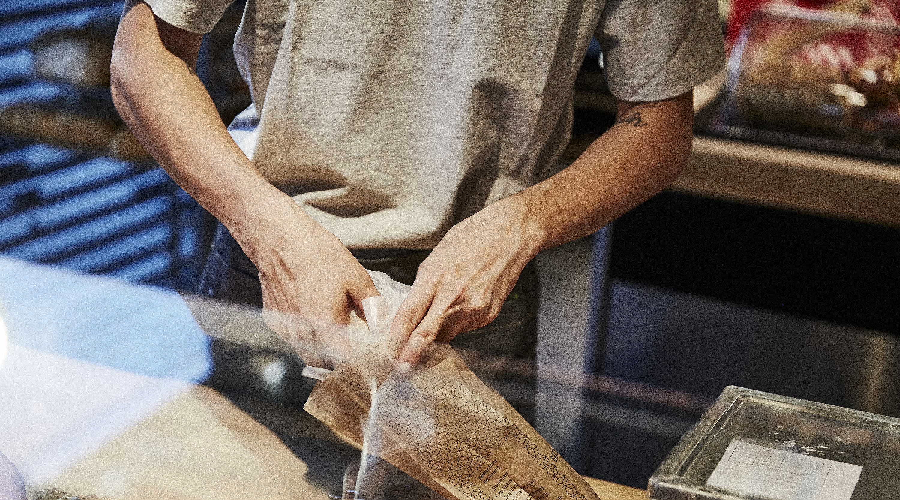 Person packt Backwaren in eine Brötchentüte. 