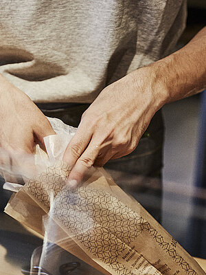 Person packt Backwaren in eine Brötchentüte. 