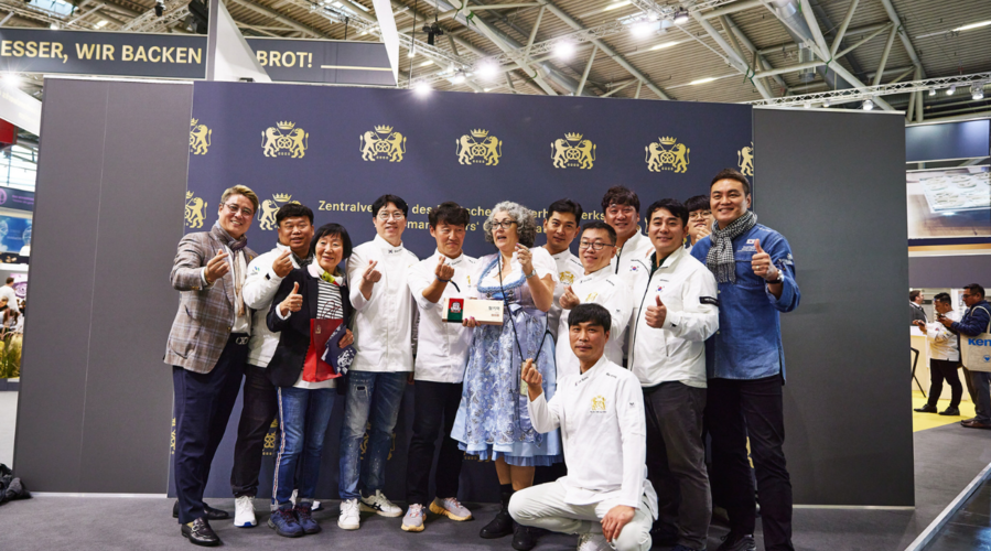 Gruppenfoto von 13 Personen auf der Iba 2023 in Bäckerkleidung